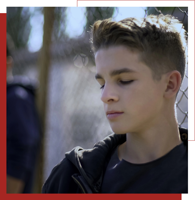 Young boy next to chain fence